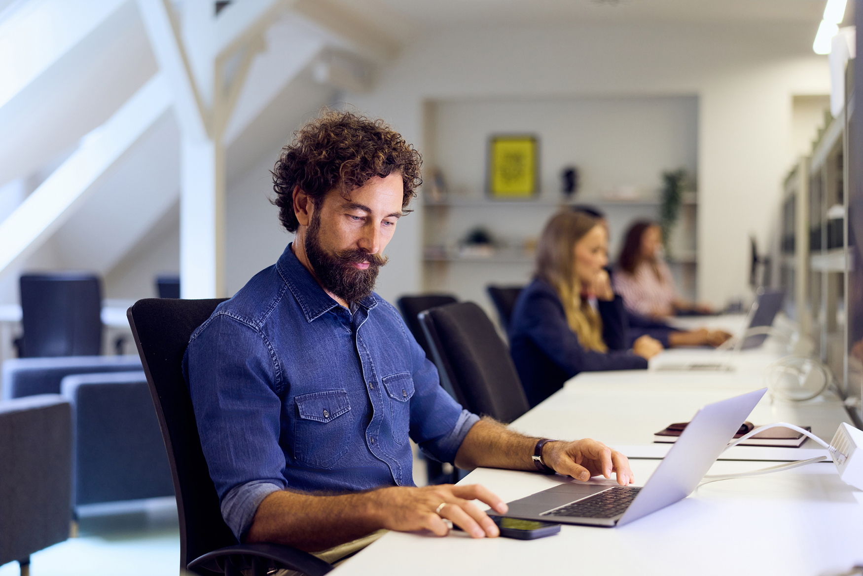 Professional using a shared desk in a flexible office, illustrating how Microsoft Places supports desk booking and workplace coordination.